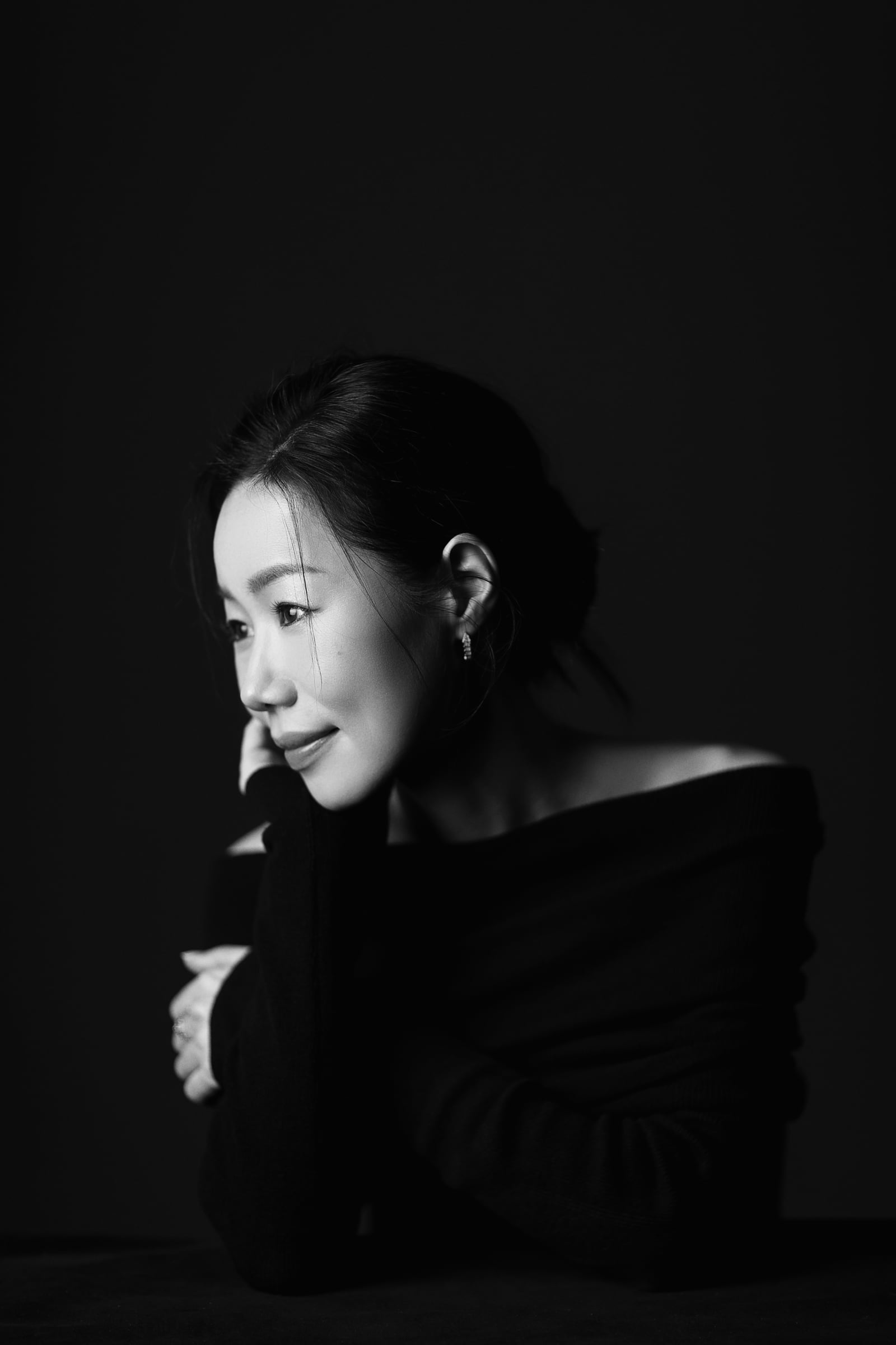 黒い服をまとい横を向く中倉志保のモノクロームポートレート